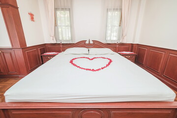 A bed decorated with heart-shaped rose petals at a wedding ceremony in Thailand.