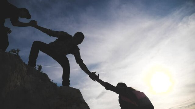 teamwork help business lifestyle travel silhouette concept. group team of tourists lends a helping hand climb the cliffs mountains. teamwork people climbers climb to lifestyle the top overcoming