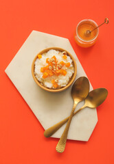 Bowl with boiled rice and pumpkin on color background