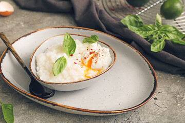 Bowl with boiled rice and egg on grey background