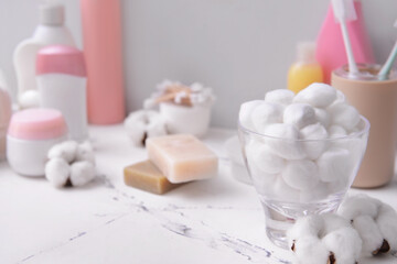 Cotton balls with cosmetics on table in bathroom