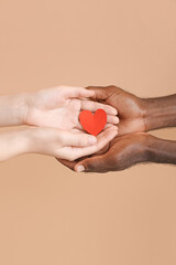 Hands of Caucasian woman and African-American man with heart on color background. Racism concept