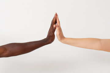 Caucasian woman and African-American man giving high-five to each other on light background. Racism...