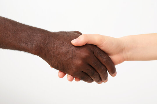 Caucasian woman and African-American man shaking hands on light background. Racism concept