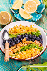 close-up of summer salad of blueberries and corn in a white bowl on a wooden table, macro