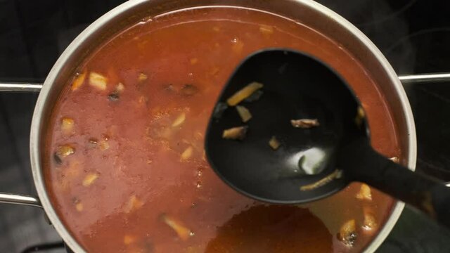Shef Cooks and mixing Healthy vegetable tomato soup food in bowl in kitchen. Close up POV
