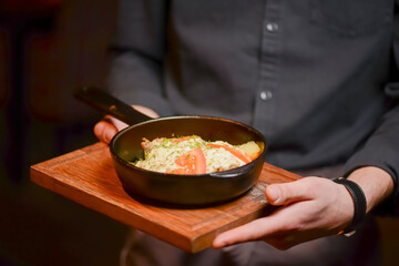 Waiter serving vegetable and meat stew in a frying pan. Concept for a tasty and healthy meal.