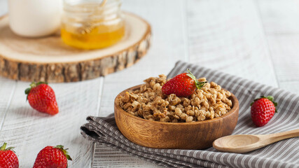 Homemade granola in a wooden bowl with strawberries on wooden background. The concept of a healthy Breakfast. Copyspace.