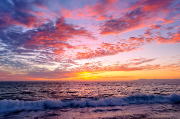 A Colorful Ocean Sunset Sky as a Gentle Wave Rolls to Shore
