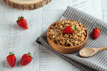 Homemade granola in a wooden bowl with strawberries on wooden background. The concept of a healthy Breakfast. Copy space