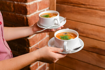 Man holding two bowls of soup. Waiter serving fresh hot soup in a diner or restaurant. Healthy delicious dinner.