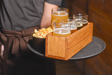 Beer selection with popcorn snack on a board. Different kinds of beer in glasses in a restaurarant.