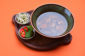 Fresh vegetable soup made of potatoes, mushrooms, carrot, red bell pepper and leek in bowl with parsley.