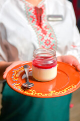 Delicious strawberry panna cotta in a glass. Waitress serving sweet traditional Italian dessert in...