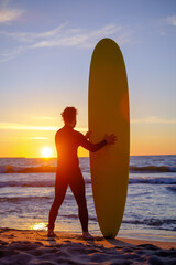 Bearded surfer on beach during sunset