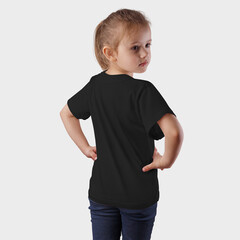 Mockup black children's t-shirt on a posing girl in blue jeans, on a background in the studio.