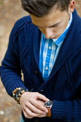 Fashion portrait of young businessman handsome model man in casual cloth suit with accessories on hands, steel watches,grey jeans and bracelets.
