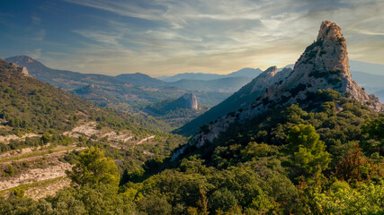 A dramatic landscape in the Dentelles de Montmirail, a beautiful chain of rock faces in the Vaucluse region of Provence, France, popular for vineyards, hiking and climbing. - obrazy, fototapety, plakaty