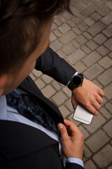 Fashion portrait of young businessman handsome model man in casual cloth suit with accessories on hands, steel watches,grey jeans and bracelets