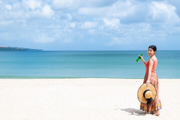 Fototapeta na wymiar 夏の海で飲み物を飲む女性