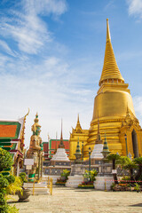 A demon guardian statue with a Great golden stupa in Wat Phra Kaew against the sky, Temple of the...