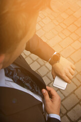 Fashion portrait of young businessman handsome model man in casual cloth suit with accessories on hands, steel watches,grey jeans and bracelets