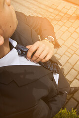 Fashion portrait of young businessman handsome model man in casual cloth suit with accessories on hands, steel watches,grey jeans and bracelets