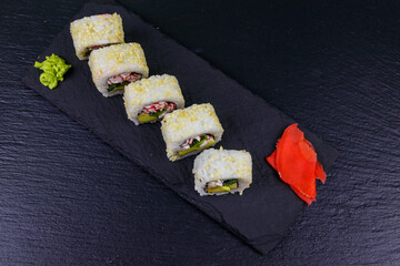 Uramaki sushi rolls with surimi on a black slate. Top view