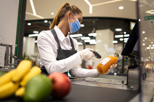 Cashier in supermarket wearing mask and gloves fully protected against corona virus. Working during covid-19 pandemic.