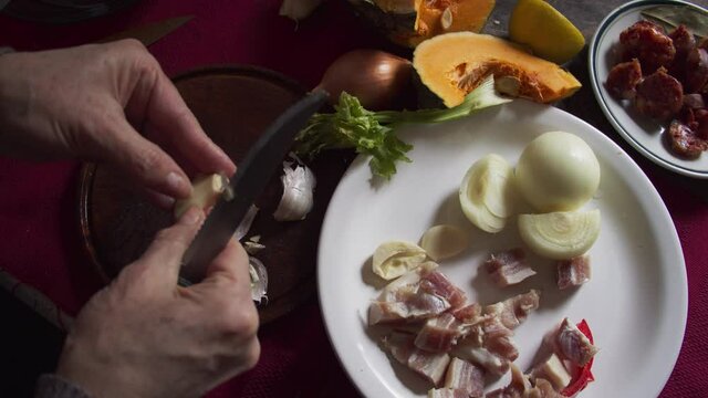 Woman with peeled garlic knife, homemade, natural daylight, food ingredients.