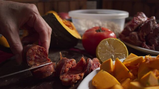 woman cutting red chorizo on a wooden board