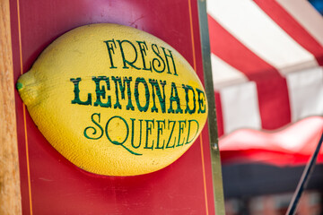 Fresh squeezed lemonade sign with white and red tent on background
