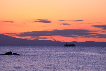 夕焼けに染まる空と港へ向かう船