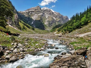 Manali, India - June 14th 2019: Crossing river by ropes in a scenic valley with mighty Indian Himalayan Mountains and blue sky. Hiking in a most scenic valley in Indian Himalayas. Humpta Pass Trek.
