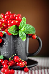 Fresh red currants in a Cup on a dark rustic wooden table. Background with space for copying. Selective focus.