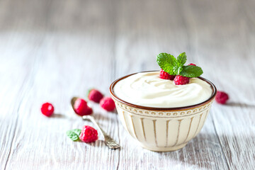 Greek yogurt in a ceramic bowl on a light wooden table.