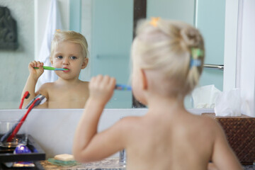 Adorable 3 years old girl brushing her teeth in bathroom.	
