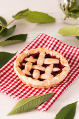 Open pie from shortcrust pastry with cherries and raspberries, a pie with a serviette on a white background