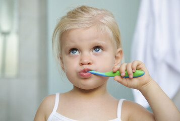 Adorable 3 years old girl brushing her teeth in bathroom.	