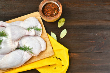 Fototapeta na wymiar Chicken legs with spices on a wooden background. Food concept. Top view, place for text.