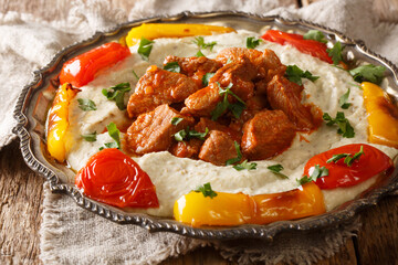 Ali Nazik kebab is small slices of tender lamb in red thick pepper sauce with mashed fragrant eggplant closeup in the plate on the table. Horizontal