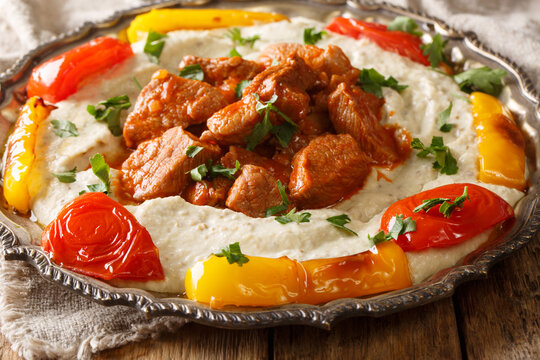 Ali Nazik kebab is tender, juicy lamb served on a bed of hot roasted eggplant that's whipped with plain yogurt closeup in the plate on the table. horizontal