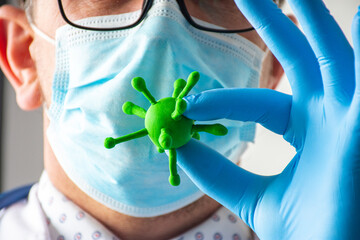 Medical worker, doctor, scientist holds in hand 3D model of virus - influenza, coronavirus, chickenpox, measles and other pathogens, other hand shows stop gesture near face in protective mask closeup - obrazy, fototapety, plakaty