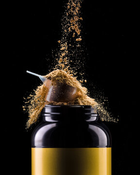Jar of chocolate protein with scoop and falling powder isolated on black