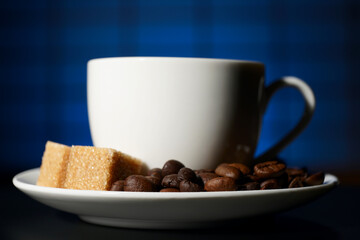 A Cup of coffee with a piece of cane sugar in a saucer on a blue background