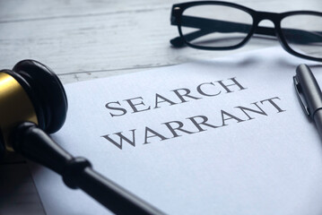 Selective focus of glasses.gavel,pen and paper written with Search Warrant on white wooden...