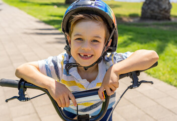 Naklejka premium Portrait of cheerful cute kid with helmet riding his bike at the park