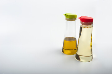 Two modern oil decanters with plastic lids. One lid is red and one is lime green.  The bottles...