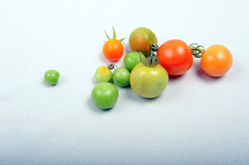 Green, orange and red tomatoes of random size.  Tomatoes of different degree of ripeness. Shot against white background.
