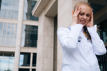 Fototapeta premium A woman in a white medical gown is holding her head.